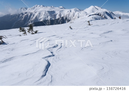 青空に映える美しい雪原の風紋と雄大な雪山、冬の山岳風景背景素材 青空に映える美しい雪原の風紋と雄大な雪山、冬の山岳風景背景素材 138726416