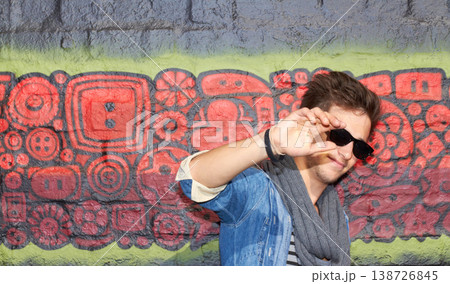 Man, fashion and street style with graffiti, cool and outdoor in urban area, sunglasses or hand. Fashionable, wall or trendy with clothes, casual or styling in amsterdam, edgy and art background Man, fashion and street style with graffiti, cool and outdoor in urban area, sunglasses or hand. Fashionable, wall or trendy with clothes, casual or styling in amsterdam, edgy and art background 138726845