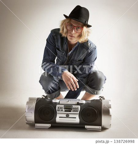 Boombox, fashion and portrait of a man in retro style in studio with music, radio or sound. Male model person on a grey background with denim outfit, glasses and hipster hat listening to audio 138726998