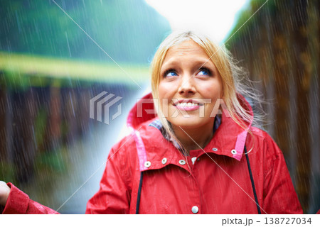 Woman, smile and raincoat for rain in nature, wet and cold from weather, winter and outdoor. Happy female person, fashion and red jacket is cool, rainfall and protection from water, face and vacation 138727034
