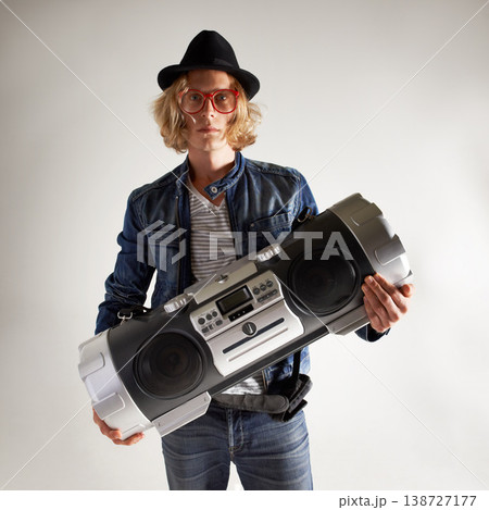 Boombox, fashion and portrait of a man in studio with music, radio or audio sound. Serious model person on grey background with denim outfit, glasses and hipster hat or retro style to listen to song Boombox, fashion and portrait of a man in studio with music, radio or audio sound. Serious model person on grey background with denim outfit, glasses and hipster hat or retro style to listen to song 138727177