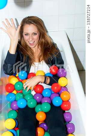 Portrait, throw ball and woman in bathtub for fashion, style and trendy hipster at home. Happy person in tub with color, sphere or plastic with body in bathroom, relax and cool clothes in Canada. Portrait, throw ball and woman in bathtub for fashion, style and trendy hipster at home. Happy person in tub with color, sphere or plastic with body in bathroom, relax and cool clothes in Canada. 138727214