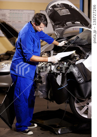 Document, man and mechanic check engine of car, repair and maintenance. Checklist, technician and serious person on motor vehicle hood, reading inspection list or fix transport at auto service garage Document, man and mechanic check engine of car, repair and maintenance. Checklist, technician and serious person on motor vehicle hood, reading inspection list or fix transport at auto service garage 138727266