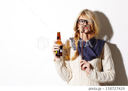Portrait, mustache and a bottle of beer with a woman in studio isolated on a white background of space for mockup. Face, alcohol and costume with a young drunk person drinking at a party or event 138727420