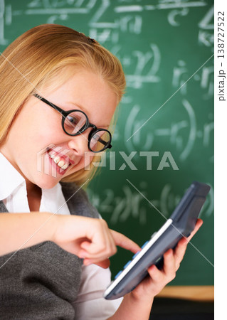 child, girl and calculator by chalkboard for happy education, learning and problem solving or solution. Smart student or child with glasses and excited for school, typing numbers or math in classroom 138727522