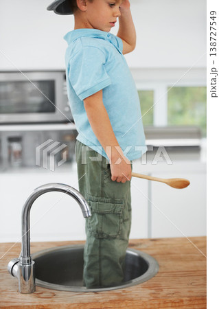 Kids, fantasy and a boy in the sink of a kitchen in his home for playing a game with his imagination. Children, creative and wooden spoon with a youth using his mind to invent fun in an apartment 138727549