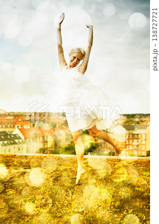 Portrait, freedom and jump with a woman on a roof in the city and fun against a bokeh effect. Smile, neighborhood or arms raised and a happy young person with energy outdoor to dance in summer Portrait, freedom and jump with a woman on a roof in the city and fun against a bokeh effect. Smile, neighborhood or arms raised and a happy young person with energy outdoor to dance in summer 138727721