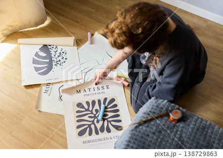 Artist reviews print selection on floor under gentle illumination 138729863