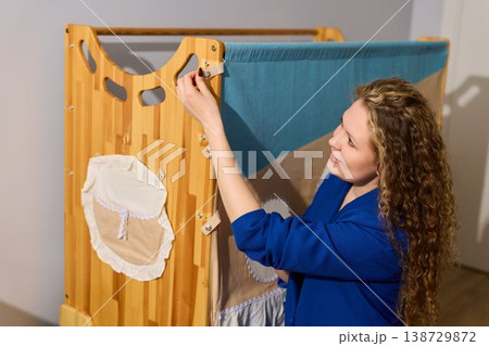 Joyful Woman Attaching Storage Pocket to Baby Play Area 138729872