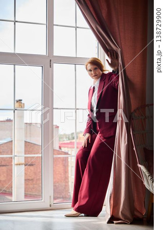 Businesswoman with red hair reviews notes by window in city Businesswoman with red hair reviews notes by window in city 138729900