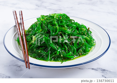 Chuka salad, made from fresh seaweed, with sesame dressing, served on a white plate, with chopsticks, no people, Chuka salad, made from fresh seaweed, with sesame dressing, served on a white plate, with chopsticks, no people, 138730011