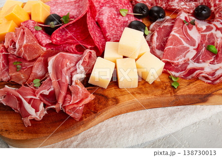 Assorted, sliced meat appetizer, prosciutto, salami and ham, with cheese and olives, on a wooden board, breakfast, top view, close-up, no people, 138730013