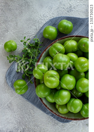 Tkemali, green cherry plum, in a bowl, on a gray table, top view, natural light, no people, 138730023