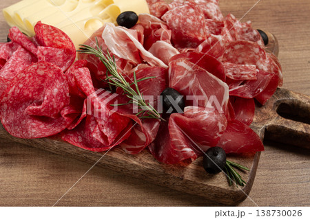 Assorted meat, appetizer, prosciutto, salami and ham, with maasdam cheese and olives, on a wooden board, breakfast, top view, close-up, no people 138730026
