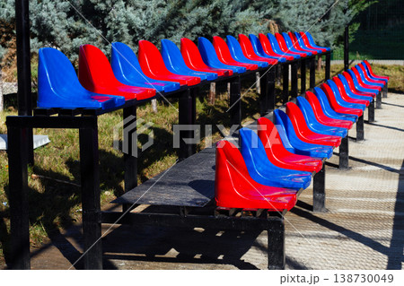 Bright colored seating arrangements lined up in a sports area on a sunny day Bright colored seating arrangements lined up in a sports area on a sunny day 138730049