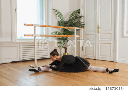 Young ballerina in tutu skirt stretching practicing ballet positions dancing in dance class. Young classical dancer woman in dance studio. Ballet class training Ballet school concept 138730184