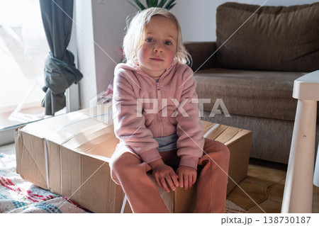Curious 4 year old girl sitting on a huge delivery box and wondering what is inside Curious 4 year old girl sitting on a huge delivery box and wondering what is inside 138730187
