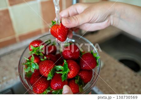 Washing fresh strawberries under running water in kitchen sink, hygiene and healthy eating concept 138730569