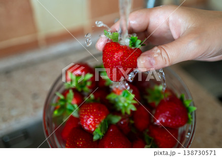 Washing fresh strawberries under running water in kitchen sink, hygiene and healthy eating concept Washing fresh strawberries under running water in kitchen sink, hygiene and healthy eating concept 138730571