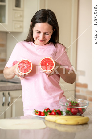 Cheerful woman shows grapefruit halves on her chest to promote healthy eating and lifestyle Cheerful woman shows grapefruit halves on her chest to promote healthy eating and lifestyle 138730581