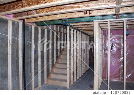 Interior view of an unfinished basement construction site featuring wooden framing, exposed walls, and a staircase leading to the upper level 138730882