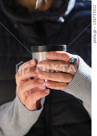 close-up of a thermos cup in his hands 138731012