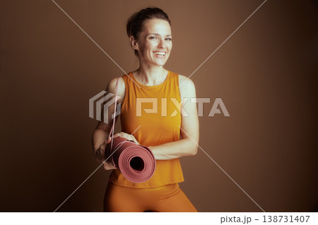 Focused Woman in Orange Activewear with Mat Focused Woman in Orange Activewear with Mat 138731407
