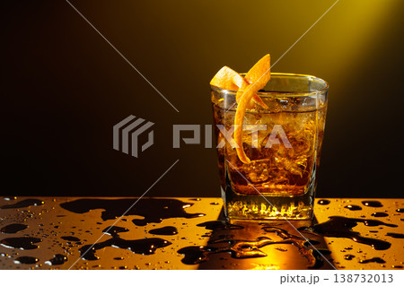 Old fashioned cocktail in a sweating glass on a wet black table. 138732013