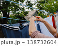 Woman attaches clothes with clothespins to ropes for drying outside 138732604