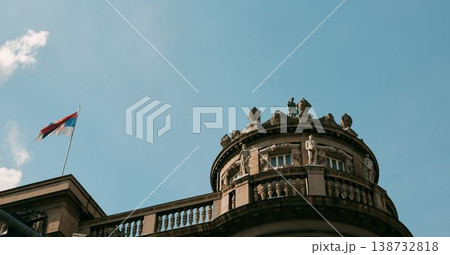 Decorative historic building dome with sculptures and Serbian flag under blue sky in Belgrade. Concept of heritage, culture and authority 138732818