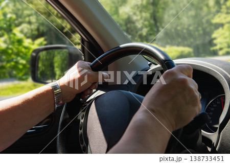 Hands on steering wheel driving car close up road travel concept Hands on steering wheel driving car close up road travel concept 138733451