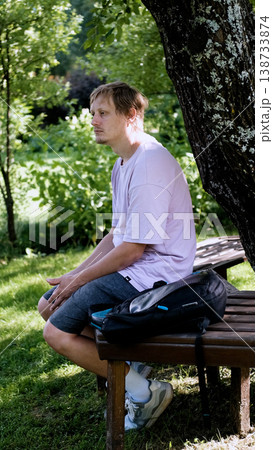 Relaxing man in a park on a bench in summer, enjoying the fresh air, vacation, or relaxing alone in the garden. A thoughtful, smiling, or calm man in nature, resting or waiting in a natural setting. Relaxing man in a park on a bench in summer, enjoying the fresh air, vacation, or relaxing alone in the garden. A thoughtful, smiling, or calm man in nature, resting or waiting in a natural setting. 138733874
