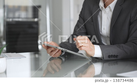 Businessman in a modern office using a digital tablet, managing data and corporate tasks, embracing mobile technology for productivity and efficient communication during a meeting, close up. 138734486