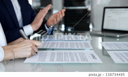 Group of business professionals sitting at an office desk with a laptop, discussing and reviewing contract documents. Collaboration and teamwork in a professional environment Group of business professionals sitting at an office desk with a laptop, discussing and reviewing contract documents. Collaboration and teamwork in a professional environment 138734495