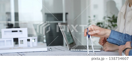 Architect woman working on blueprints and architectural model, planning a residential building project, engaged in modern design development Architect woman working on blueprints and architectural model, planning a residential building project, engaged in modern design development 138734607