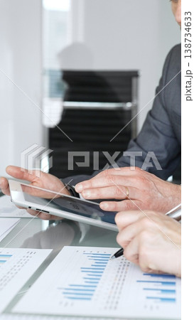 Business people reviewing and negotiating contract terms in an office meeting, focusing on agreement details and legal paperwork before signing Business people reviewing and negotiating contract terms in an office meeting, focusing on agreement details and legal paperwork before signing 138734633
