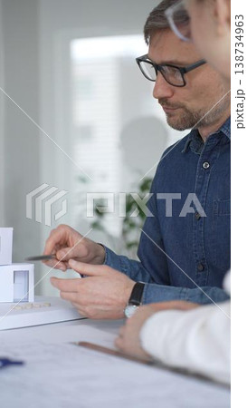 Architects collaborating on architectural plans. Designing modern building models. Drawing blueprints. Engineering innovative residential project solutions Architects collaborating on architectural plans. Designing modern building models. Drawing blueprints. Engineering innovative residential project solutions 138734963