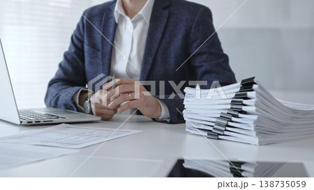 Accountant or bookkeeper calculating financial data, preparing taxes, managing business reports, and organizing paperwork with a calculator and stack of documents on an office desk. Audit and taxes Accountant or bookkeeper calculating financial data, preparing taxes, managing business reports, and organizing paperwork with a calculator and stack of documents on an office desk. Audit and taxes 138735059