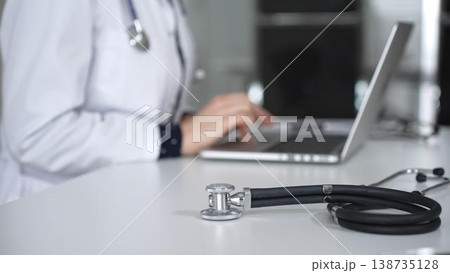 Stethoscope is on the doctor's working table opposite the female physician working on a laptop. Medicine concept 138735128