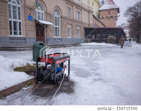 【ウクライナ】西部リヴィウ旧市街の街角の積雪の石畳の上に置かれたジェネレーター 138735580