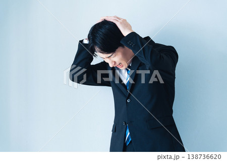 頭を抱えるスーツ姿の若い男性 頭を抱えるスーツ姿の若い男性 138736620