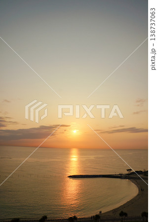 弧を描く砂浜と夕日が染めるオレンジの空の海景色 138737063