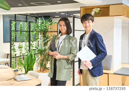 緑豊かなオフィスで笑顔を見せる若手男女 緑豊かなオフィスで笑顔を見せる若手男女 138737295
