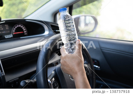 Asian woman driver hold cold water for drink in car, dangerous and risk an accident. 138737918