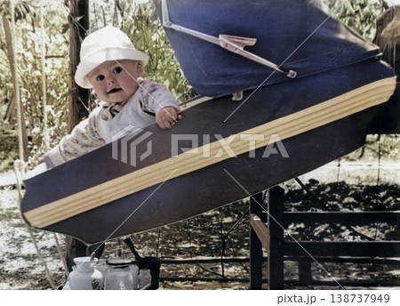 A vintage portrait of a little boy wearing a Panama hat, sitting in a stroller. Retro photo from 1968. A vintage portrait of a little boy wearing a Panama hat, sitting in a stroller. Retro photo from 1968. 138737949
