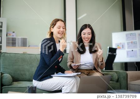 Two women collaborating on a project on sofa at home, brainstorming with a laptop and notebook Two women collaborating on a project on sofa at home, brainstorming with a laptop and notebook 138739709