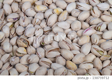 Tight macro pistachios texture, repeating pattern of closed and slightly open shells, pale tones with subtle purple streaks, crisp detail ideal for backgrounds and food design 138739712