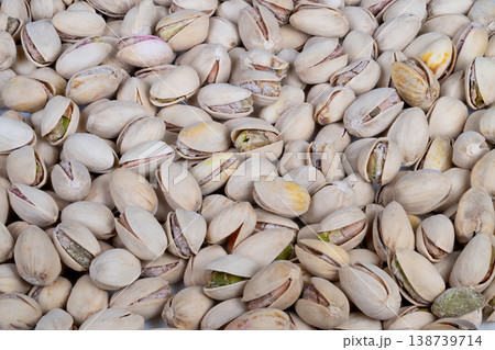 Pistachio shells scattered. Cracked shells display green kernels. Salted roasted pistachios with crispy texture. Premium gourmet pistachio snack on neutral surface Pistachio shells scattered. Cracked shells display green kernels. Salted roasted pistachios with crispy texture. Premium gourmet pistachio snack on neutral surface 138739714