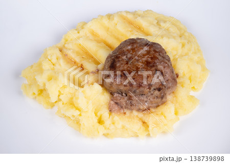 Delicious meat dish. Closeup of crispy cutlet resting on smooth mashed potatoes. Detailed view of browned crusted cutlet atop creamy mashed potatoes on white plate 138739898