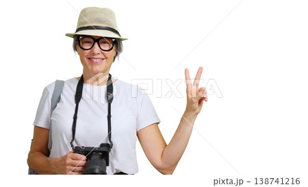 Happy senior woman tourist holding camera making peace or victory sign 138741216